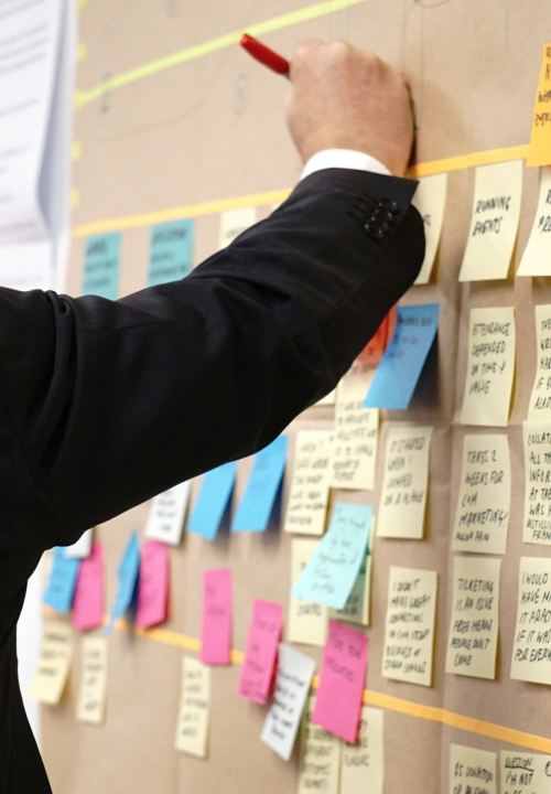 Homem realizando anotações em um post-it na parede